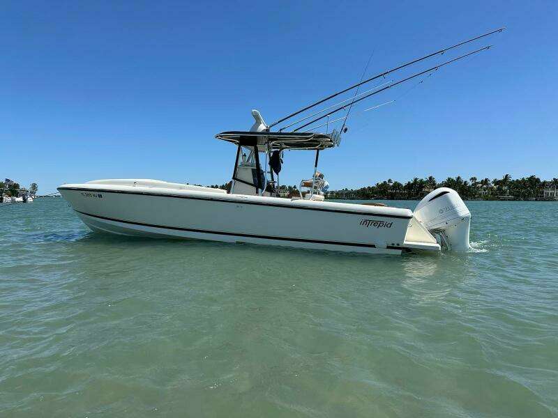 2004 Intrepid 32 Cuddy boat on water, clear sky, fishing rods visible.