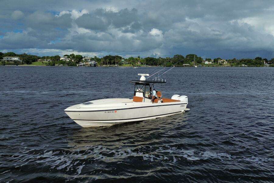 2004 Intrepid 32 Cuddy boat cruising on a scenic waterway under cloudy skies.