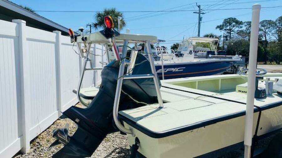 1983 Maverick 18 Flats Boat with outboard motor, parked near a white fence.