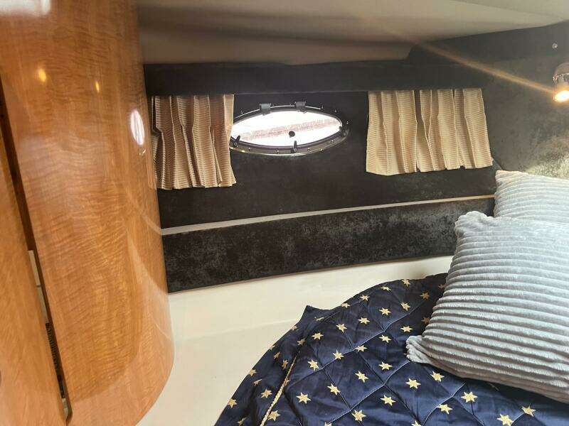 2003 Regal Commodore 3860 cabin interior with bed, porthole, and wooden cabinetry.