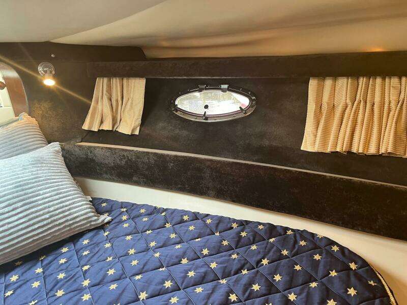 Interior cabin of 2003 Regal Commodore 3860 with bed, pillows, and porthole window.