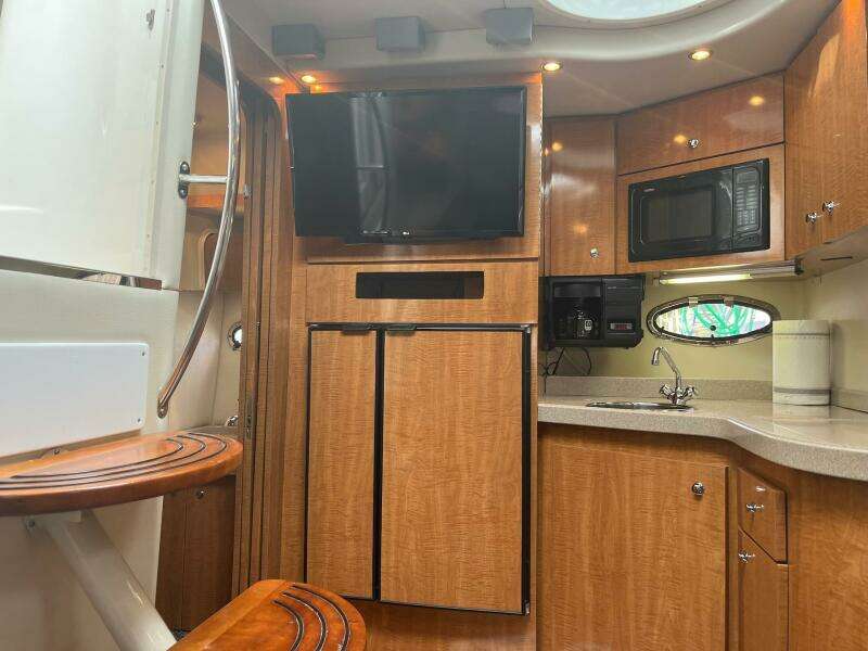 Interior of 2003 Regal Commodore 3860 yacht with kitchen, TV, and wooden cabinetry.