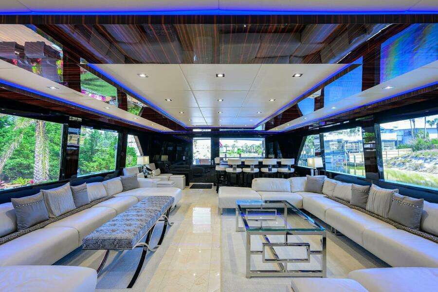 Luxurious interior of 1997 Broward 108 Raised Pilothouse yacht with modern seating and glass tables.