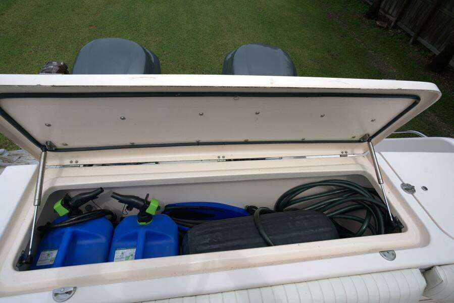Open storage compartment on 2007 Grady-White Express 330 boat with blue containers and hose.