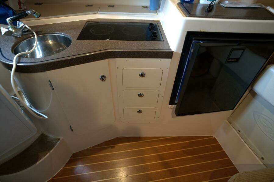 2007 Grady-White Express 330 boat kitchen with sink, stove, and mini fridge.