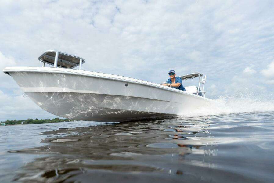 2025 BlueZones Boatworks 16' Flats boat cruising on water under cloudy sky.