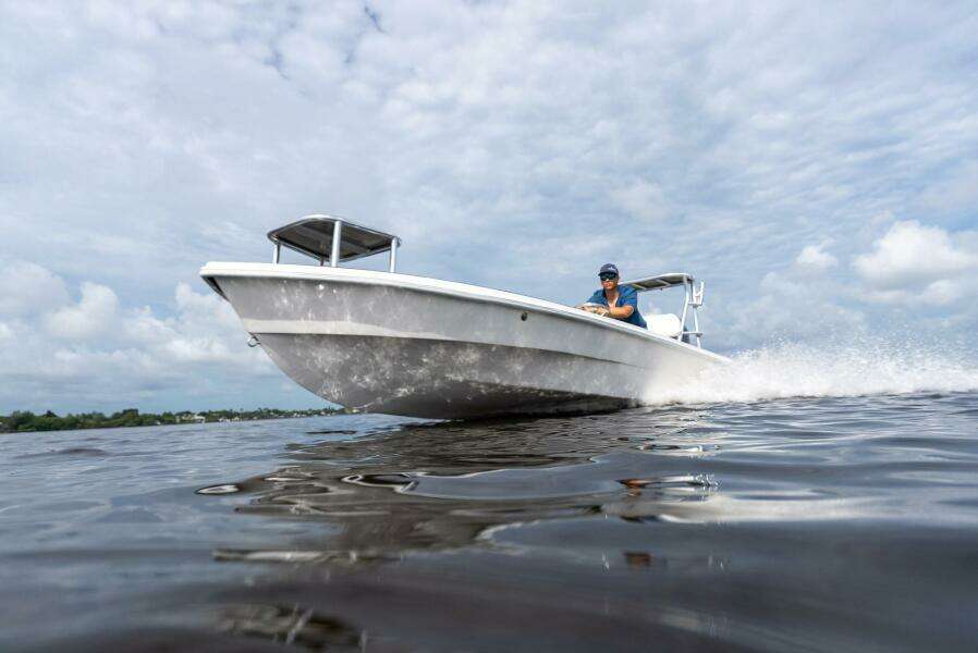 2025 BlueZones Boatworks 16' Flats boat cruising on open water under cloudy skies.