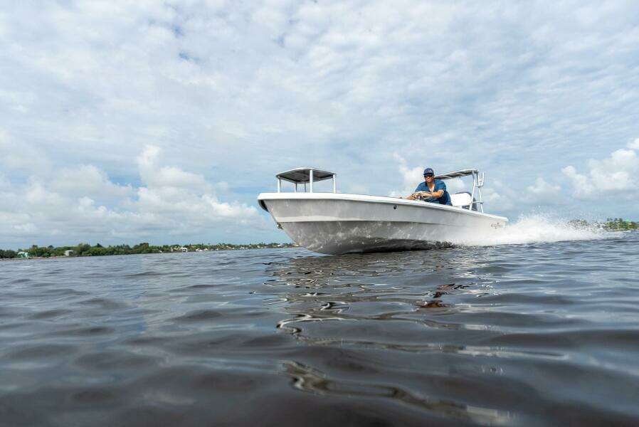 2025 BlueZones Boatworks 16' Flats cruising on open water under a cloudy sky.