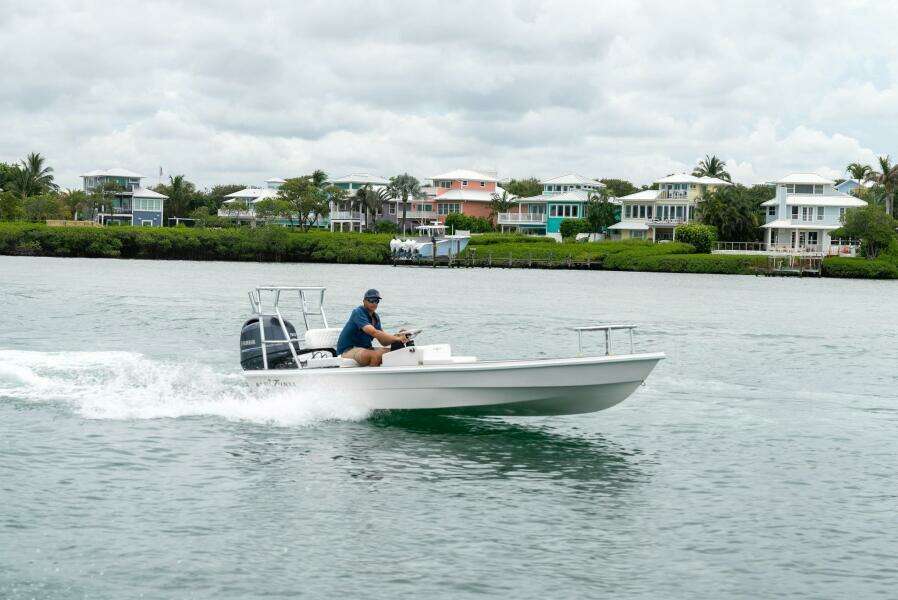 2025 BlueZones Boatworks 16' Flats cruising on water near coastal homes.