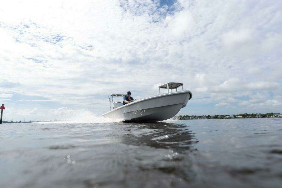 2025 BlueZones Boatworks 16' Flats boat cruising on open water under a cloudy sky.