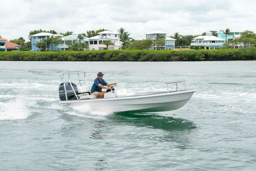 2025 BlueZones Boatworks 16' Flats cruising on water near coastal homes.