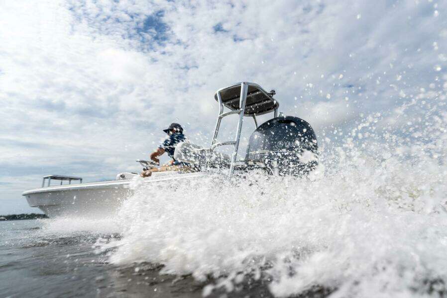 2025 BlueZones Boatworks 16' Flats speeding through water, creating splashes under a cloudy sky.