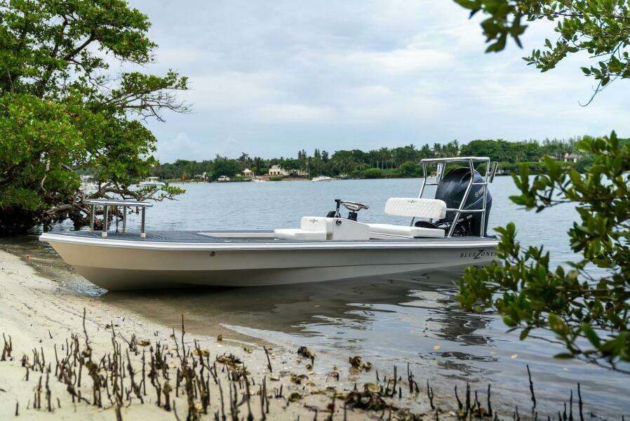2025 BlueZones Boatworks 16' Flats boat docked by a serene shoreline.