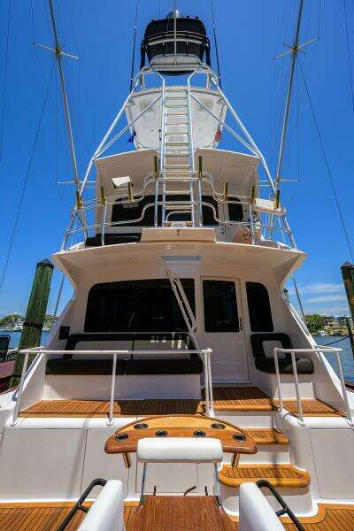 2004 Viking 65 Enclosed Bridge w/Tower yacht, rear view, docked under clear blue sky.