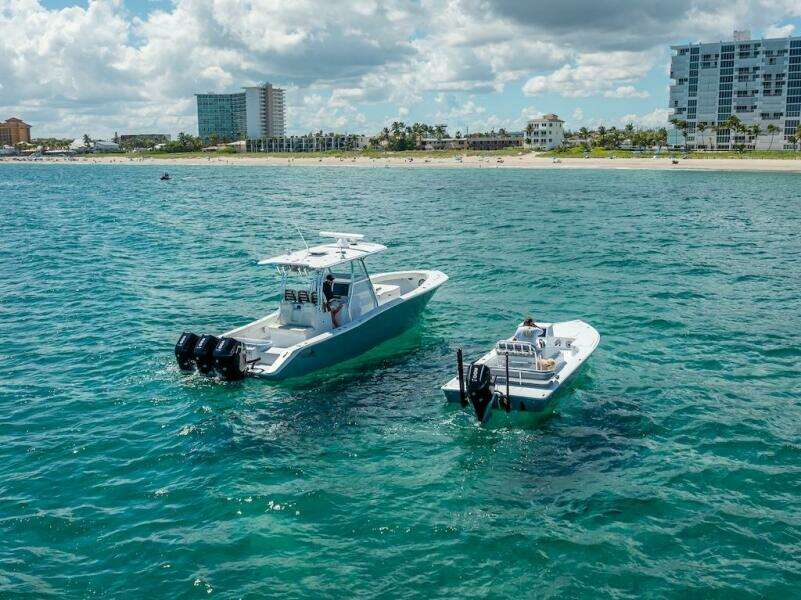 2025 Billfish 39 Center Console with Tower on ocean near beach and buildings.