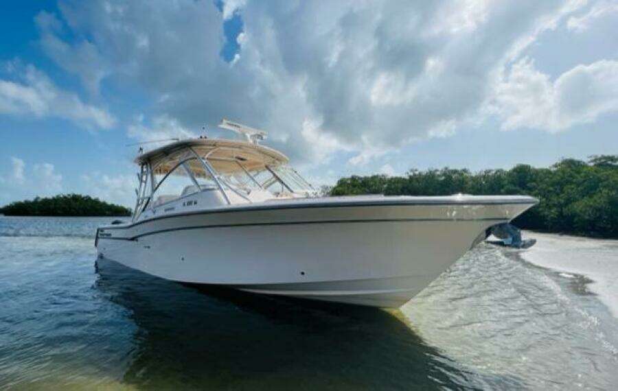 2014 Grady-White Freedom 335 boat anchored near a scenic shoreline under a partly cloudy sky.