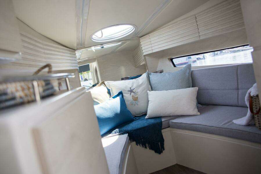Cozy interior of 2023 Real 35 Special Deck (SD) boat with cushions and natural light.