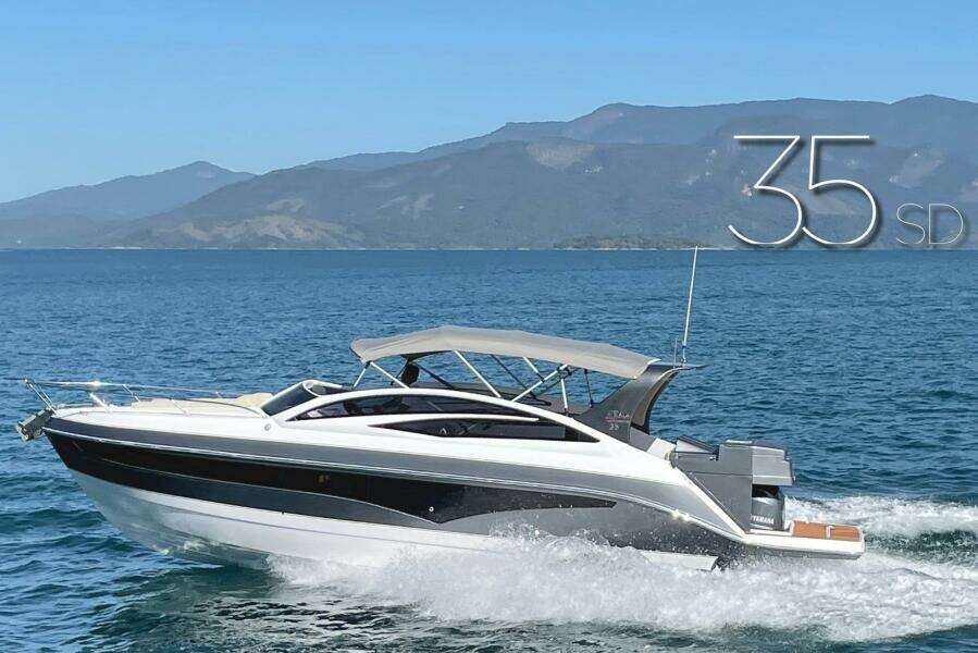 2023 Real 35 Special Deck (SD) boat cruising on a scenic lake with mountains in the background.