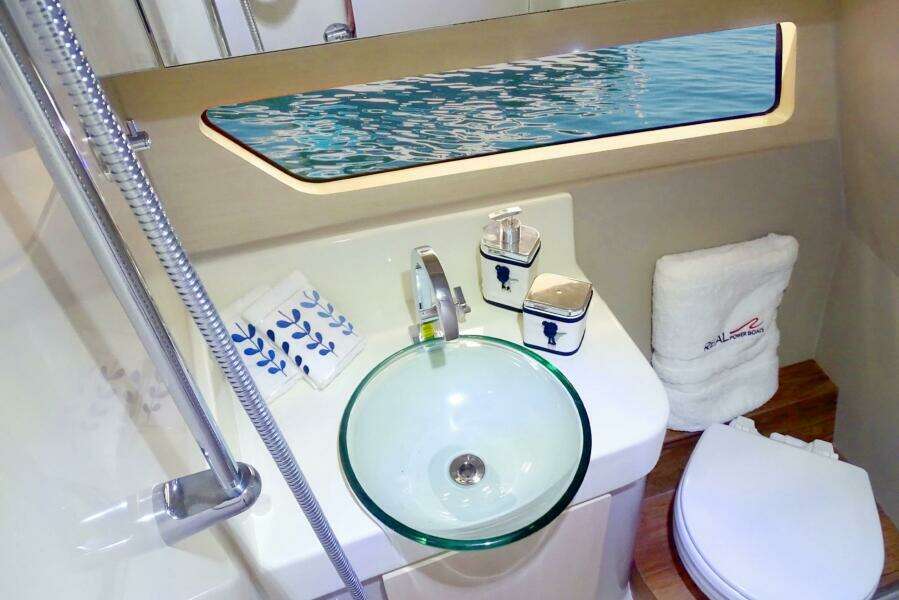 Modern bathroom on 2023 Real 35 Special Deck (SD) boat with glass sink and ocean view.