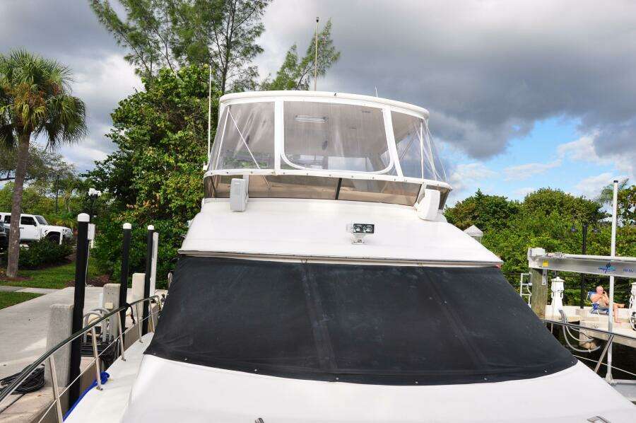 1998 Sea Ray 480 Sedan Bridge docked, front view with canopy and lush background.
