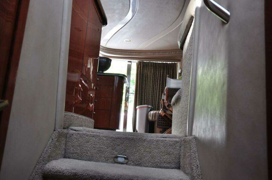 Interior stairs of 1998 Sea Ray 480 Sedan Bridge yacht with carpet and wooden cabinets.