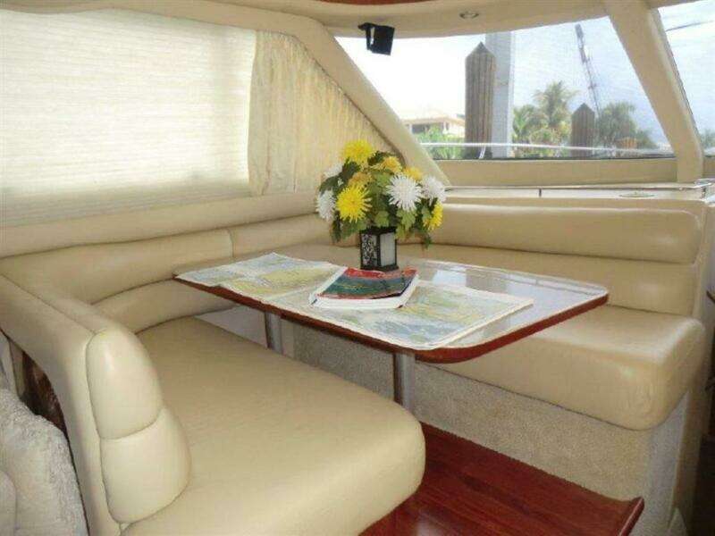 Interior of 1998 Sea Ray 480 Sedan Bridge with dining area and floral centerpiece.