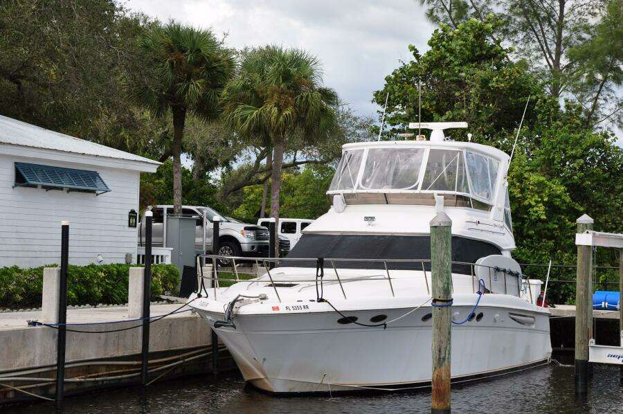 1998 Sea Ray 480 Sedan Bridge docked at a marina with lush greenery.
