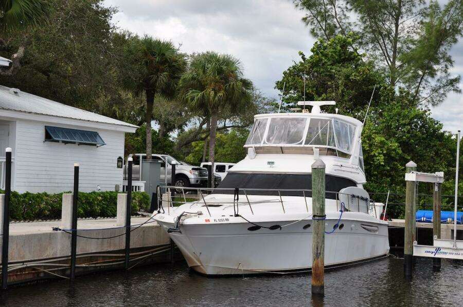 1998 Sea Ray 480 Sedan Bridge yacht docked near a white house.
