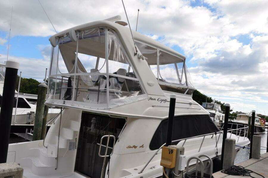 1998 Sea Ray 480 Sedan Bridge yacht docked at marina under cloudy sky.
