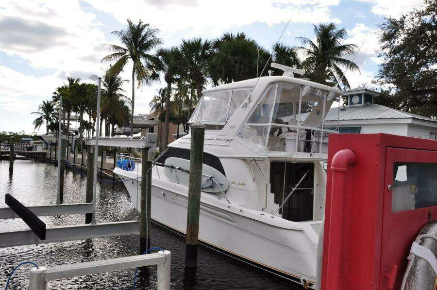 1998 Sea Ray 480 Sedan Bridge docked at a marina with palm trees.