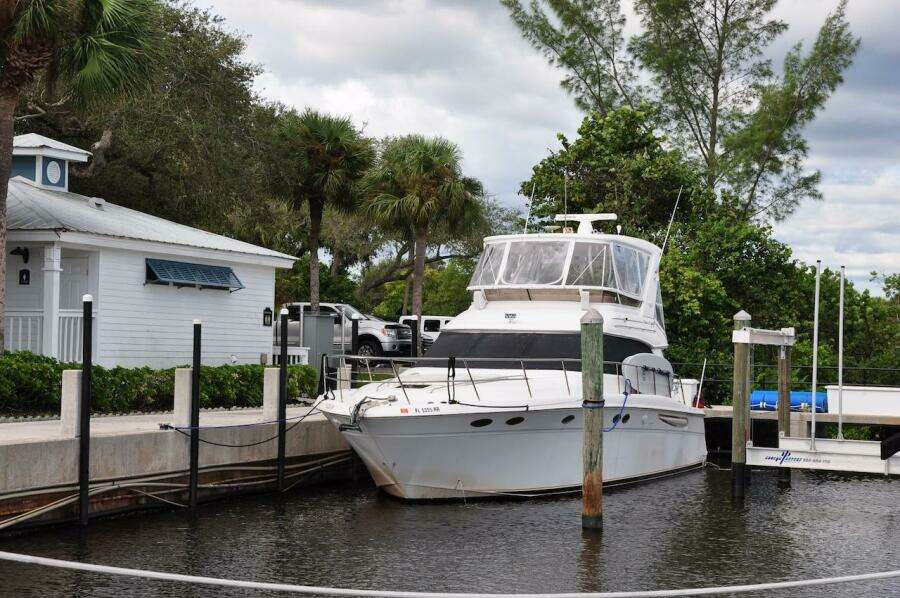 1998 Sea Ray 480 Sedan Bridge docked at a marina with lush greenery.