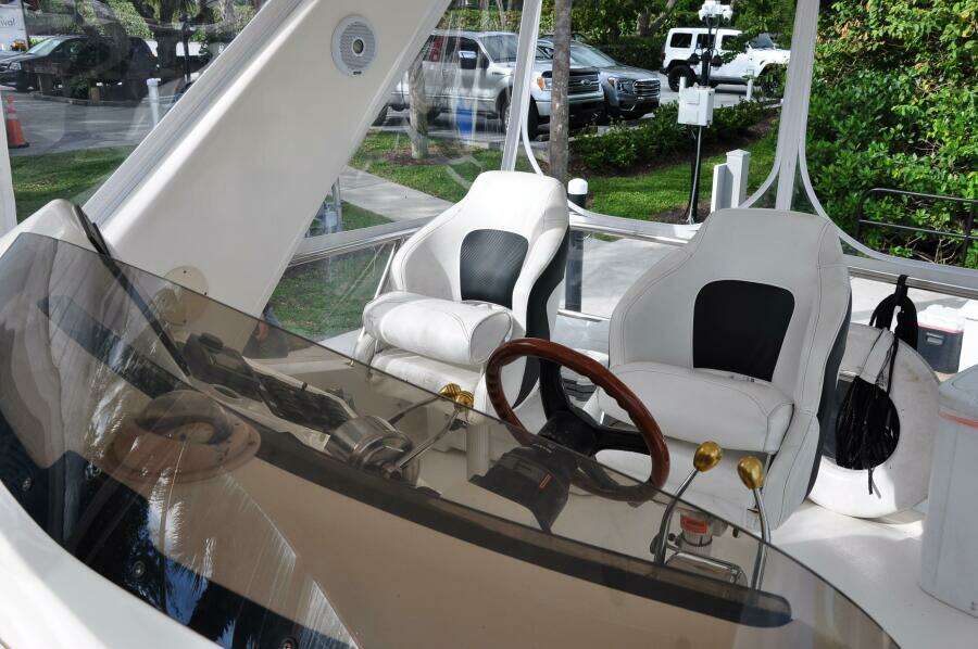 1998 Sea Ray 480 Sedan Bridge helm with dual captain chairs and wooden steering wheel.