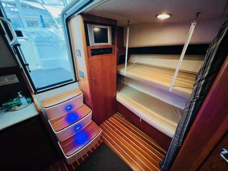 Interior of 2003 Tiara Yachts 3800 Open with bunk beds and illuminated steps.