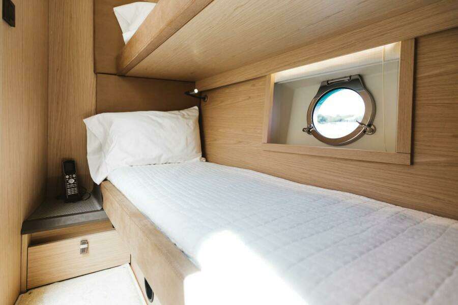 Cozy cabin interior of 2015 Beneteau Monte Carlo 5 yacht with porthole and single bed.