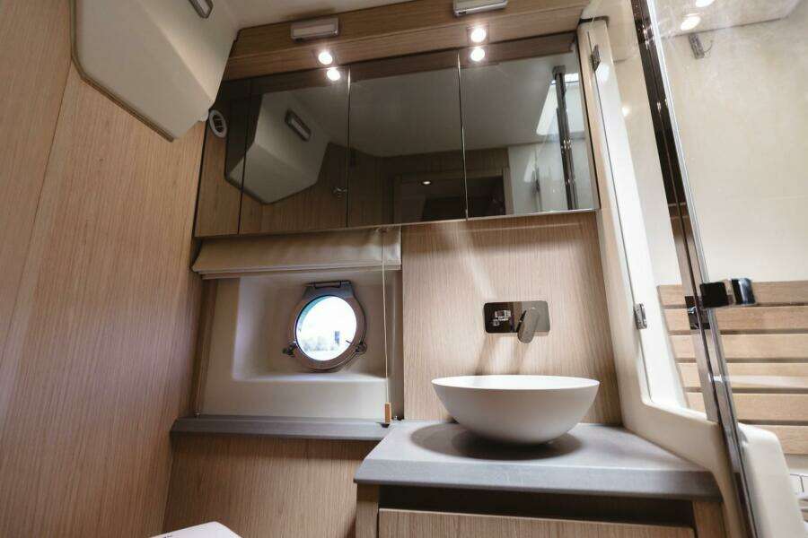 Luxurious bathroom in 2015 Beneteau Monte Carlo 5 yacht with modern fixtures and porthole window.