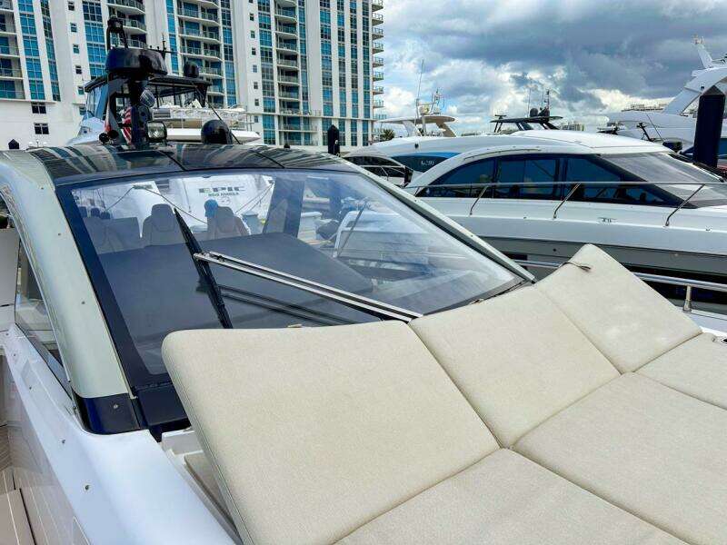 2023 Azimut Verve 47 yacht with sunbathing area, docked near modern buildings.