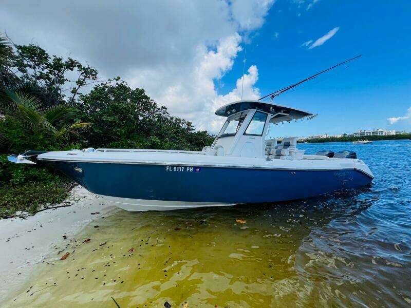 2012 Everglades 295 Center Console boat on sandy shore with lush greenery.