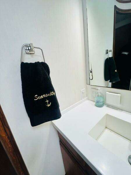 Bathroom interior of 1988 Bertram 54' yacht with "Searenity" towel and modern sink.