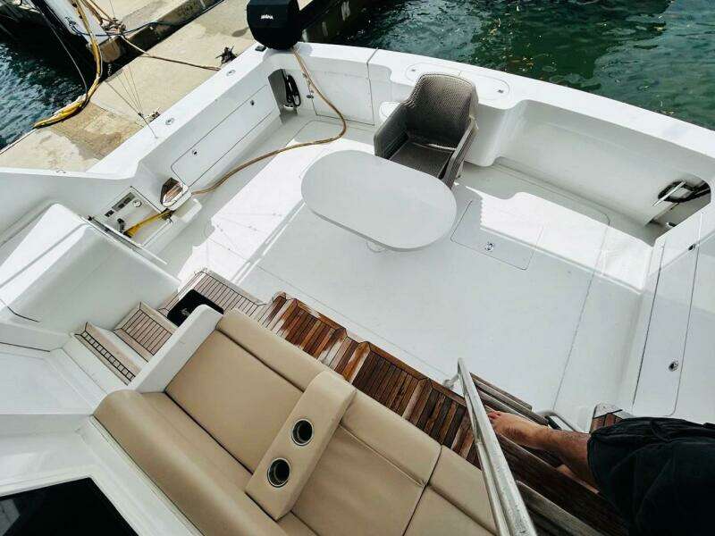 1988 Bertram 54' yacht deck with seating and table, docked at marina.