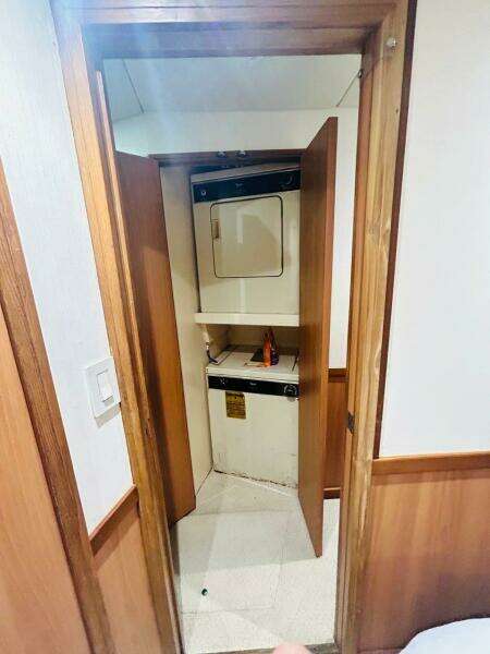 Laundry area inside 1988 Bertram 54' yacht with wood paneling and compact washer-dryer.