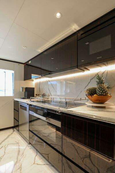 Luxurious kitchen in 2025 Majesty 120 yacht with sleek cabinets and marble flooring.