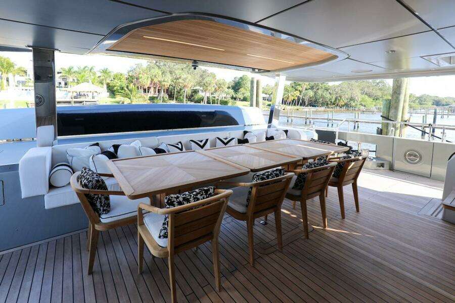 Luxurious 2025 Majesty 120 yacht deck with elegant dining area and scenic waterfront view.