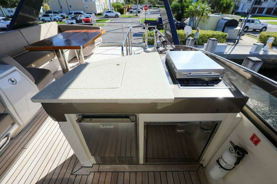 Outdoor kitchen on 2016 Marquis 660 Sport Yacht with grill and seating area.