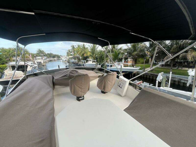 2017 Marquis 500 Sport Yacht deck with covered seating, docked in a scenic marina.