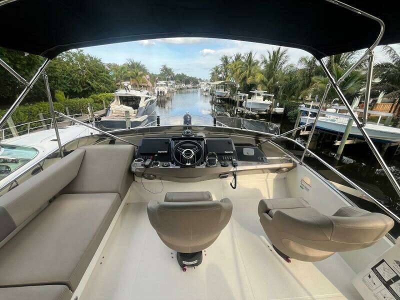 2017 Marquis 500 Sport Yacht helm with dual seats, docked in a scenic marina.