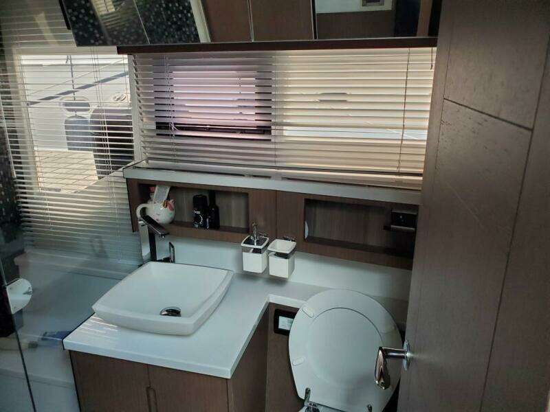 Modern bathroom interior of 2020 Galeon 500 Fly yacht with sink, toilet, and window blinds.