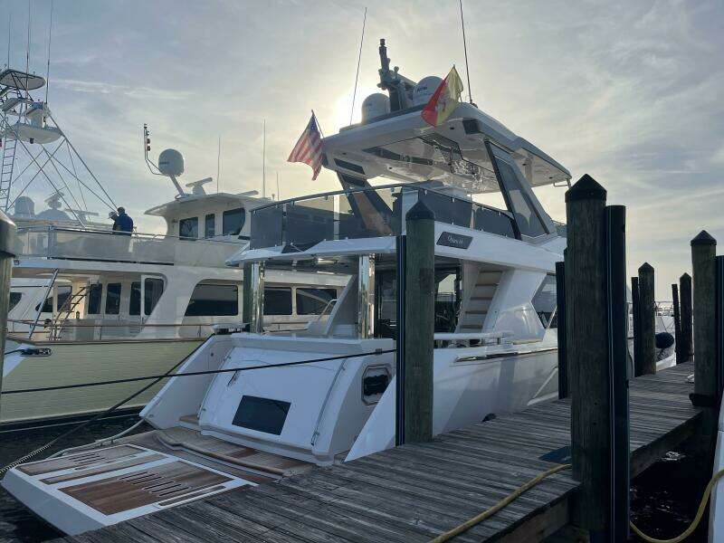 2024 Aicon 66 Vivere yacht docked at marina under a cloudy sky.