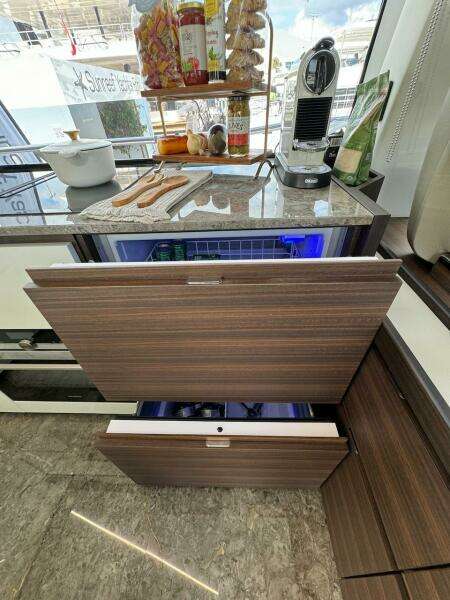 Luxury yacht kitchen with modern appliances, featuring wood cabinetry and marble countertops on Aicon 66 Vivere 2024.