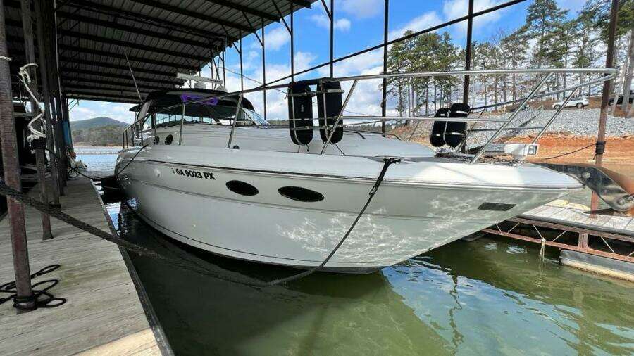 2003 Sea Ray 380 Sundancer docked in a marina, surrounded by calm water and trees.