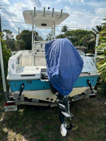 2016 Release 208 RX boat with covered motor, parked on grass.